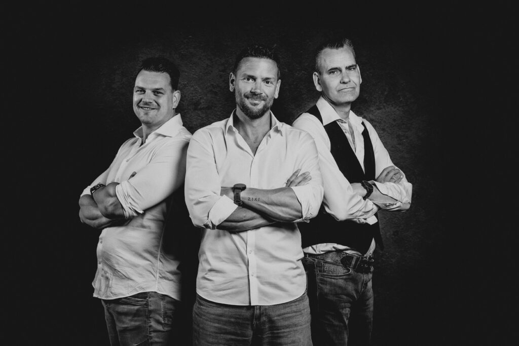 Zwart-wit bandportret van drie mannen met de armen over elkaar