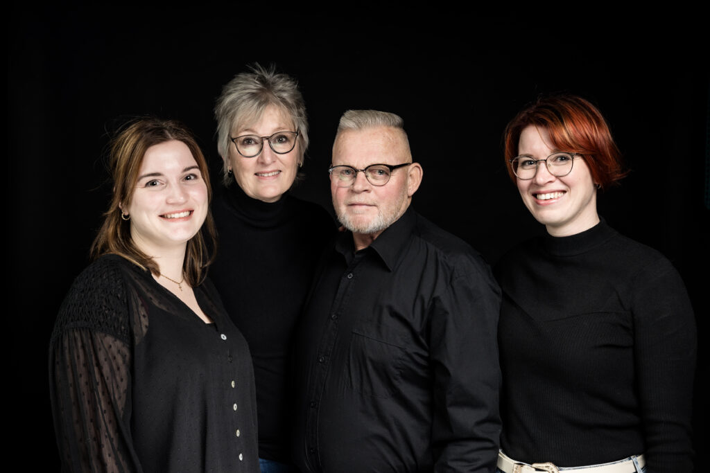 Familie van vier in zwarte kleding voor een zwarte studioachtergrond