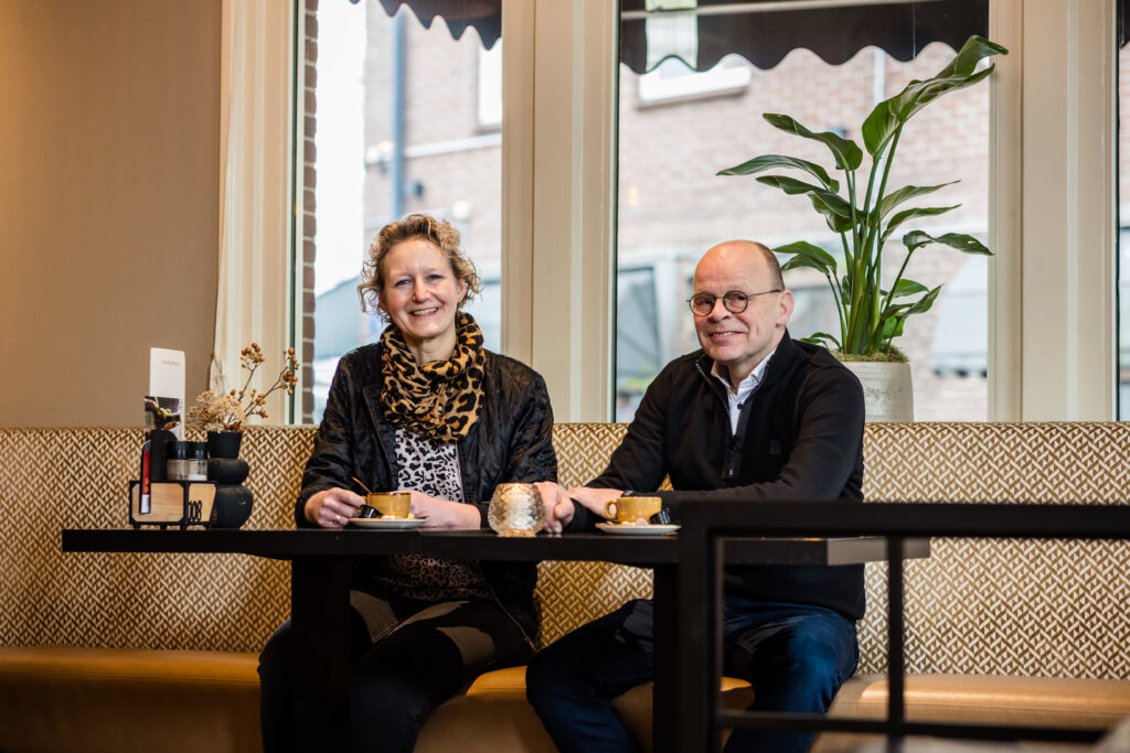 Ondernemersstel zit lachend met koffie aan een tafel in een lunchroom